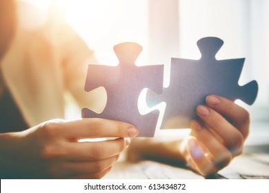 Woman is trying to connect couple puzzle piece. Symbol of association and connection. Concept of business strategy.