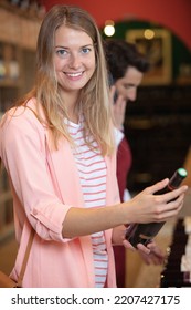 Woman Trying To Decide Which Bottle Of Wine To Buy