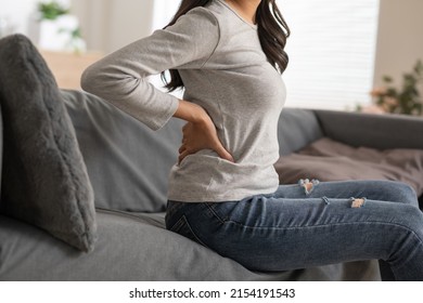 A woman is trying to exercise by twist her upper body, but she has a bit ache and pain on her back. She needs massage and cracking her back to release her tight. She's pushing on the back bone. - Shutterstock ID 2154191543