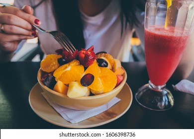 Woman Trying Exotic Dish In Street Cafe. Adult Lady Taking Piece Of Fruit From Plate And Chewing Food While Resting In Street Restaurant.