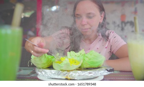 Woman Trying Exotic Dish In Street Cafe. Adult Lady Taking Piece Of Hot Dish From Cabbage Leaf And Chewing Food While Resting In Street Restaurant