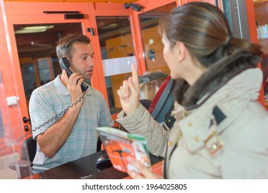 Woman Trying To Get Attention Of Man In Ticket Office