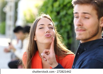 Woman trying to kiss a man and he is rejecting her outdoor in a park
