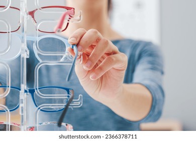 Woman trying new fashion glasses at the eyewear shop, hands close up - Powered by Shutterstock