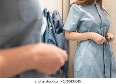 Woman trying on a blue dress in a store.