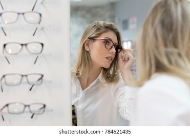 Woman Trying On Glasses In Optical Store