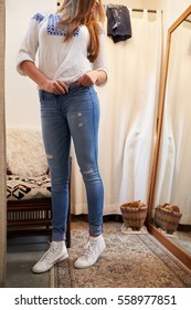 Woman Trying On Jeans In A Changing Room Looking In Mirror