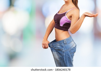 A Woman Trying On Jeans Of The Wrong Size In A A Blur Background. Oversized Clothing Concept.