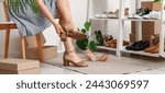 Woman trying on stylish summer sandals in shoe store