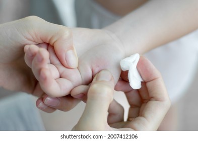 The woman is trying to pull the splinter out of the child's hand. A splinter in a child's hand