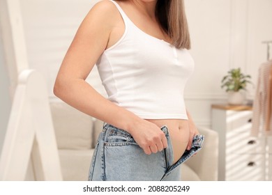 Woman trying to put on tight jeans at home, closeup