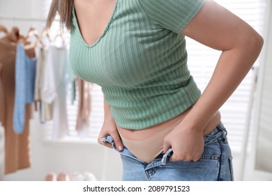 Woman Trying To Put On Tight Jeans At Home, Closeup