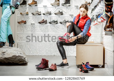Woman trying shoes for mountain hiking sitting in the fitting room of the modern sports shop ストックフォト © 