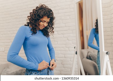 Woman trying to squeeze into old pair of jeans. fitness and diet concept - Shutterstock ID 1360935314