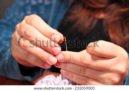 Woman  trying to thread a needle, close up