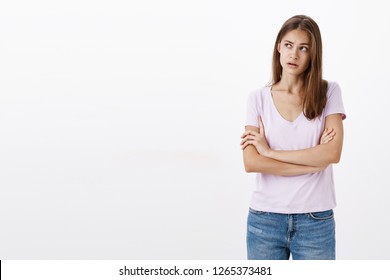 Woman trying understand what boyfriend meant. Focused clueless, confused attractive stylish young woman holding hands crossed on chest raising eyebrow, gazing at upper left corner recalling situation