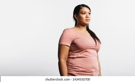 Woman In Tshirt Standing Against White Background. Portrait Of Obese Woman Looking Away.