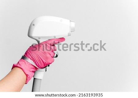 A woman tunes a laser hair removal machine. She holds a working part of the epilator in her hands and poses for a photo. Body Care. Underarm Laser Hair Removal.