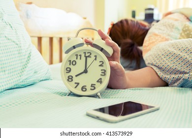 Woman Turn Off Alarm Clock On Bed In Morning