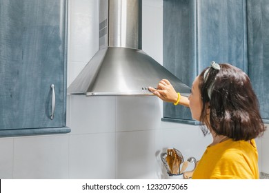 Woman turn on exhaust ventilation in the kitchen