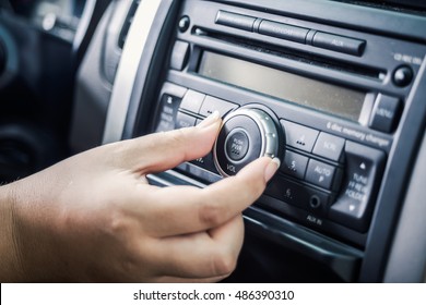 Woman Turning Button Of Radio In Car