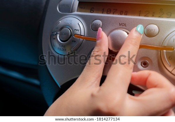 woman turning button of radio in car. Car Radio\
Listening. Car Driver Changing Radio Stations on His Vehicle\
Multimedia System
