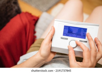 Woman Turning Knob On New Weather Compensating Programmable Room Thermostat Intelligent Control For Heating And Hot Water Looking At Gas Consumption For 2021 And 2022 Compare Evolution And Trends