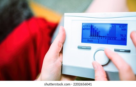 Woman Turning Knob On New Weather Compensating Programmable Room Thermostat Intelligent Control For Heating And Hot Water Looking At Gas Consumption For 2021 And 2022 Compare Evolution And Trends