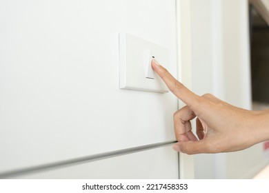 Woman Turning Off Light Switch In A Home