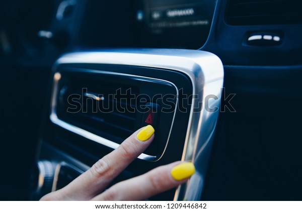 Woman turning on car emergency lights. Modern\
car interior
