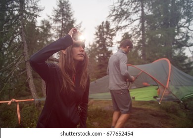 Woman Turning On Headlamp Flashlight Near Hanging Tent Camping. Group Of Friends People Summer Adventure Journey In Mountain Nature Outdoors. Travel Exploring Alps, Dolomites, Italy.