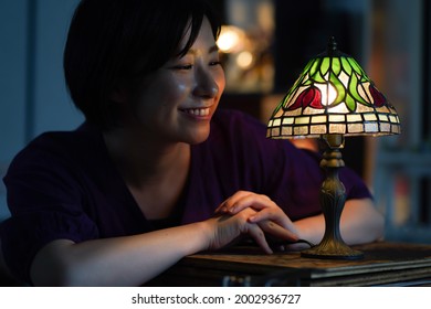 Woman Turning On A Stained Glass Lamp 