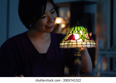 Woman Turning On A Stained Glass Lamp 
