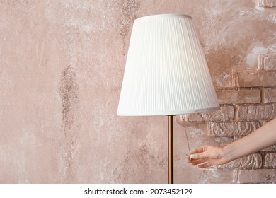 Woman Turning On Torchier Near Pink Wall