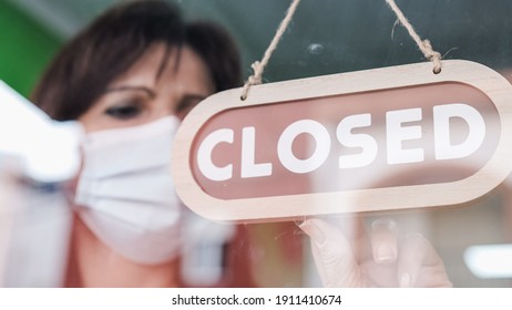 Woman turning a sign from open to closed. Covid-19. - Shutterstock ID 1911410674