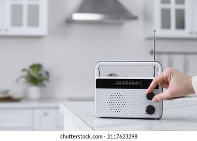 Woman turning volume knob on radio in kitchen, closeup. Space for text - Shutterstock ID 2117623298