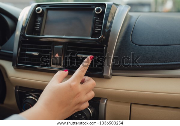 Woman turns on air conditioning in the car.\
Modern car interior