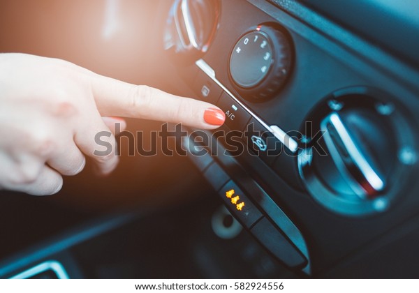 Woman turns on air conditioning in her car.\
Modern car interior