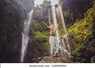 Woman in turquoise dress at the Sekumpul waterfalls in jungles on Bali island, Indonesia. Bali Travel Concept
