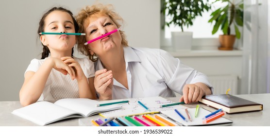 Woman tutor or foster parent mum helping cute caucasian school child girl doing homework sitting at table. Diverse nanny and kid learning writing in notebook studying at home. - Powered by Shutterstock