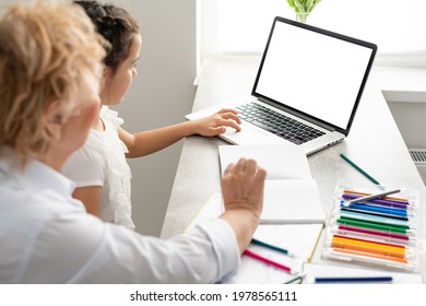 Woman Tutor Or Foster Parent Mum Helping Cute Caucasian School Child Girl Doing Homework Sitting At Table. Diverse Nanny And Kid Learning Writing In Notebook Studying At Home.