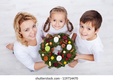 Woman With Two Kids Holding Advent Wreath - Holidays In The Family