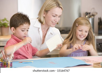 Woman And Two Young Children In Kitchen With Art Project Smiling