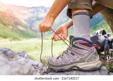 Woman tying hiking boot outdoors on trail in summer.