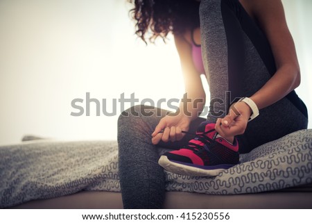 Woman tying a shoelace and preparing for fitness.