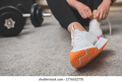 Woman tying shoelaces before exercise. Home fitness training concept. - Powered by Shutterstock