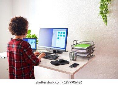 Woman Typing On Computer At An Adjustable Standing Desk, On A Work Day From Home