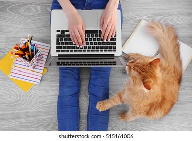 Woman Typing On Laptop And Sitting On Floor With Fluffy Cat