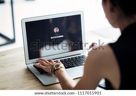 A woman is typing the password in her laptop computer. Communicate about privacy, passwords, security, business, working, data, anti-hacking, protection.