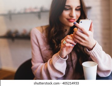 Woman Typing Write  Message On Smart Phone In A  Modern Cafe. Cropped Image Of Young  Pretty Girl Sitting At A Table With  Coffee Or Cappuccino  Using Mobile Phone.